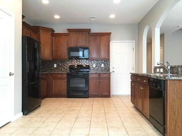 Huntersville house for rent - a large kitchen with black appliances and wooden cabinets