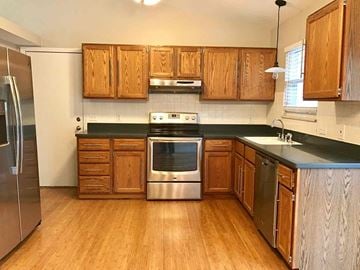 Saint Peters house for rent - a kitchen with wooden cabinets and stainless steel appliances