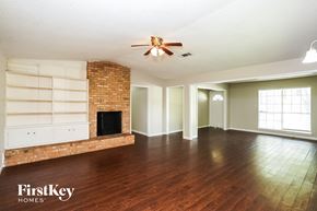 La Porte house for rent - A spacious room with a brick fireplace and wooden floors.