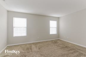 Indianapolis house for rent - a spacious room with carpet and two windows