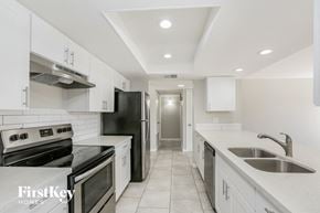 Phoenix house for rent - a kitchen with white cabinets and black appliances and white counter tops
