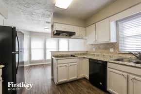 Houston house for rent - a kitchen with white cabinets and black appliances