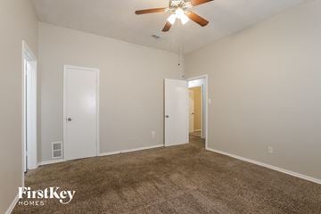 Houston house for rent - a spacious living room with carpet and a ceiling fan