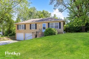 Independence house for rent - A house with a brown and beige exterior is surrounded by green grass and trees.