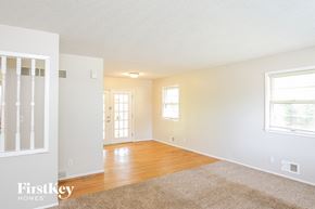 Independence house for rent - A spacious room with a rug on the floor and a door in the background.