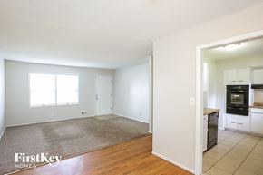 Independence house for rent - A room with a carpet and a kitchen in the background.