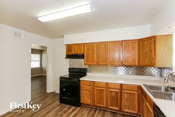 Dallas house for rent - a kitchen with wooden cabinets and a black stove and a sink