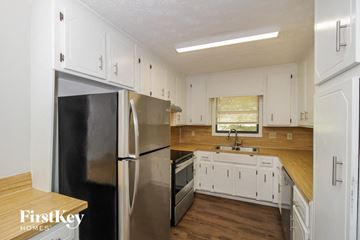Acworth house for rent - A kitchen with white cabinets and a black fridge.