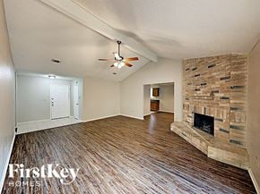 Houston house for rent - an empty living room with a stone fireplace and wood flooring