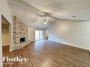 Houston house for rent - an empty living room with a fireplace and a ceiling fan