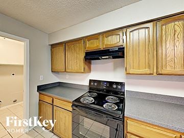 Houston house for rent - a kitchen with wooden cabinets and a black stove and oven