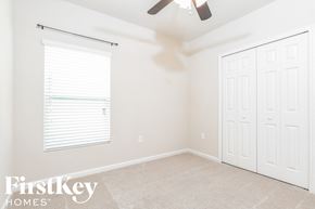 Melbourne house for rent - a bedroom with two closets and a window and a ceiling fan
