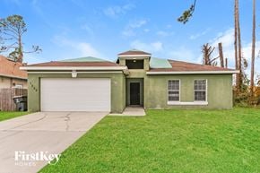 North Port house for rent - a green house with a driveway and a garage door