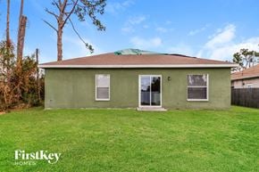 North Port house for rent - a green house with a grassy yard and a tree