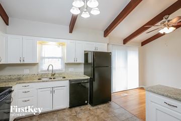 Shawnee house for rent - a kitchen with white cabinets and a black refrigerator