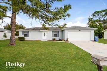 Palm Bay house for rent - a white house with a lawn and a white garage door