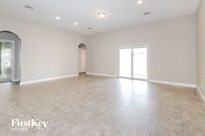 Port St. Lucie house for rent - an empty living room with tile flooring and a door to the kitchen
