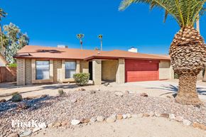 Phoenix house for rent - A house with a red garage door and a palm tree in front.