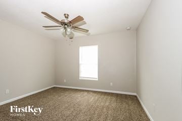 Port St. Lucie house for rent - a bedroom with a ceiling fan and a carpet
