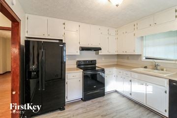 Lawrenceville house for rent - a kitchen with white cabinets and a black refrigerator