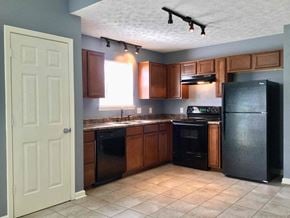 Indianapolis house for rent - A kitchen with black appliances and brown cabinets.