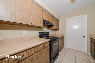 Venice house for rent - A kitchen with wooden cabinets and a black stove top oven.