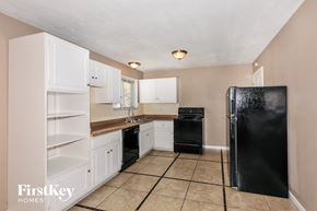 Florissant house for rent - a kitchen with white cabinets and a black refrigerator