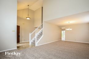Fishers house for rent - A spacious room with a staircase and a chandelier.