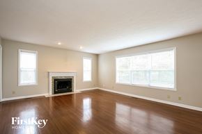 Fishers house for rent - A large empty room with a fireplace and wooden floors.