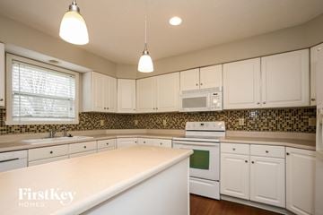 Fishers house for rent - A kitchen with white cabinets and a tiled backsplash.