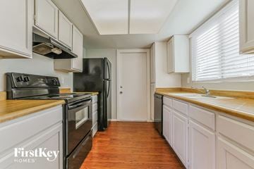 Glendale house for rent - a kitchen with white cabinets and black appliances