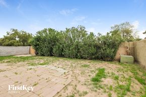 Glendale house for rent - a backyard with weeds and a fence and trees