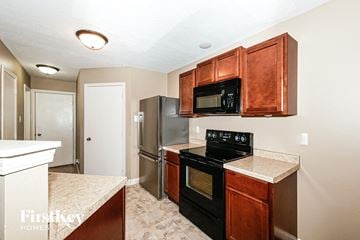 Camby house for rent - A kitchen with a black stove top oven and microwave above it.