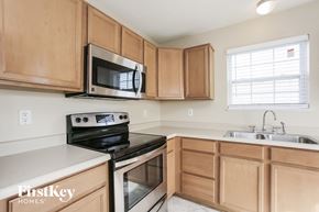 Fishers house for rent - a kitchen with wood cabinets and black appliances and a microwave