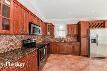 Miami house for rent - a kitchen with wooden cabinets and stainless steel appliances