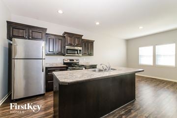 Peculiar house for rent - A kitchen with dark wood cabinets and a stainless steel refrigerator.