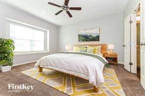 Peculiar house for rent - A bedroom with a bed, a ceiling fan, and a rug.