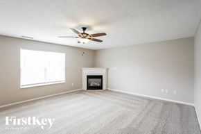 Noblesville house for rent - A spacious room with a fireplace and a ceiling fan.