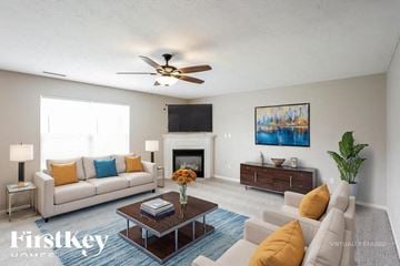 Noblesville house for rent - A living room with a white couch, a coffee table, a fireplace, and a painting on the wall.