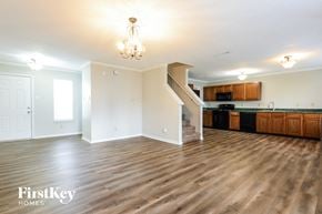 Camby house for rent - A well-lit, empty living room with wooden floors and a staircase leading to the upper level.