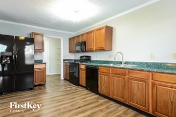 Camby house for rent - A kitchen with wooden cabinets and a black refrigerator.