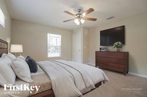 Palm Bay house for rent - A bedroom with a large bed, a ceiling fan, and a flat-screen TV mounted on the wall.