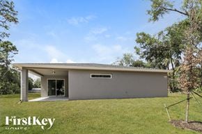 Palm Bay house for rent - A modern house with a grey exterior and a white roof is surrounded by greenery.