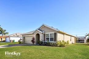 Cape Coral house for rent - a beige house with a lawn in front of it