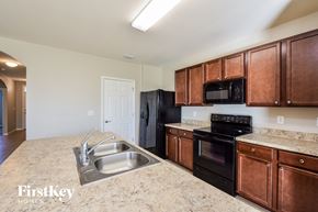 Cape Coral house for rent - a kitchen with black appliances and brown cabinets and granite counter tops