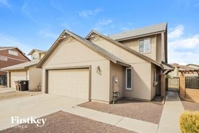 Peoria house for rent - A beige house with a garage door and a brown driveway.