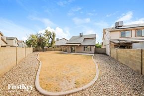 Peoria house for rent - A backyard with a gravel path and a few trees.