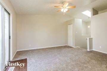 Indianapolis house for rent - a spacious living room with carpet and a ceiling fan
