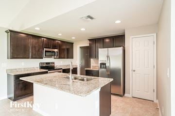 Cape Coral house for rent - a kitchen with granite counter tops and a stainless steel refrigerator