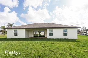 Cape Coral house for rent - a white house with a grass yard and a cloudy sky